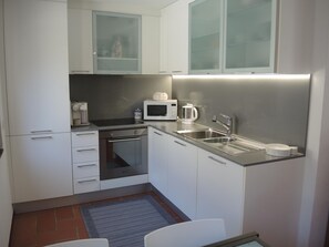 A compact kitchen with white cabinets, a microwave, a coffee maker, and a stainless steel sink. - Casa Gialla by Interhome (Locarno Tegna)