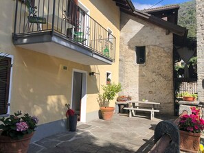 Ein Innenhof mit Steinpflaster, einem Tisch und Topfpflanzen.