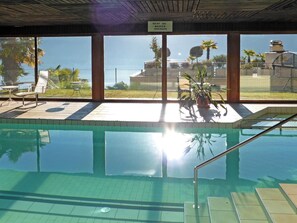 Ein Innenpool mit großen Glaswänden, einem sonnendurchfluteten Bereich und Blick auf den Ozean.