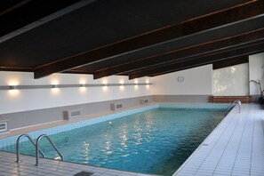 An indoor swimming pool with a tiled floor, a metal ladder, and wall-mounted lights. - ||-------------------in "Haus Erika"-------------------|| (Langenargen)