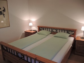 A double bed with a wooden headboard, two bedside tables with lamps, and a framed artwork on the wall. - Piccolo Mondo 1 by Interhome (Minusio)