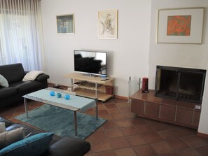 Ein Wohnzimmer mit einer Couch, einem Couchtisch, einem Fernseher, einem Kamin und Kunstwerken an den Wänden.