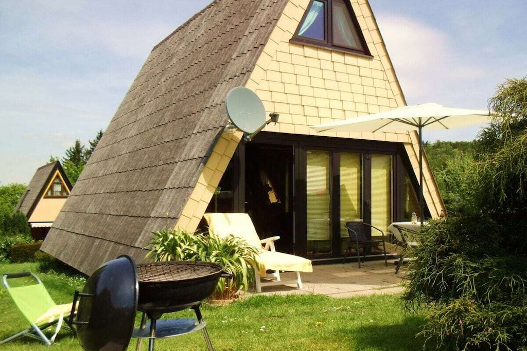 A house with a sloped roof, a satellite dish, and a patio area with a grill and outdoor furniture.
