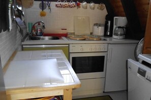 A compact kitchen with a sink, stove, and a small refrigerator. - Holiday home with 2 bedrooms (Lichtenberg)