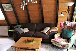 A cozy living room with a dark brown sofa, a wooden coffee table, and a colorful armchair. - Holiday home with 2 bedrooms (Lichtenberg)