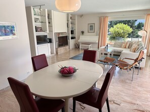 Un soggiorno moderno con zona pranzo, un pianoforte e vista sull'esterno.