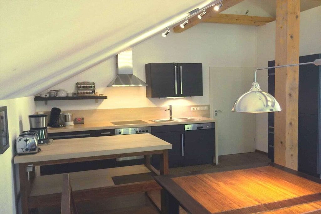 Eine kleine Küche mit Holztisch, integriertem Backofen und einer Pendelleuchte.
