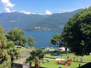 A park with a playground, a swimming pool, and a view of a lake and mountains. - Lago Maggiore by Interhome (Brissago)