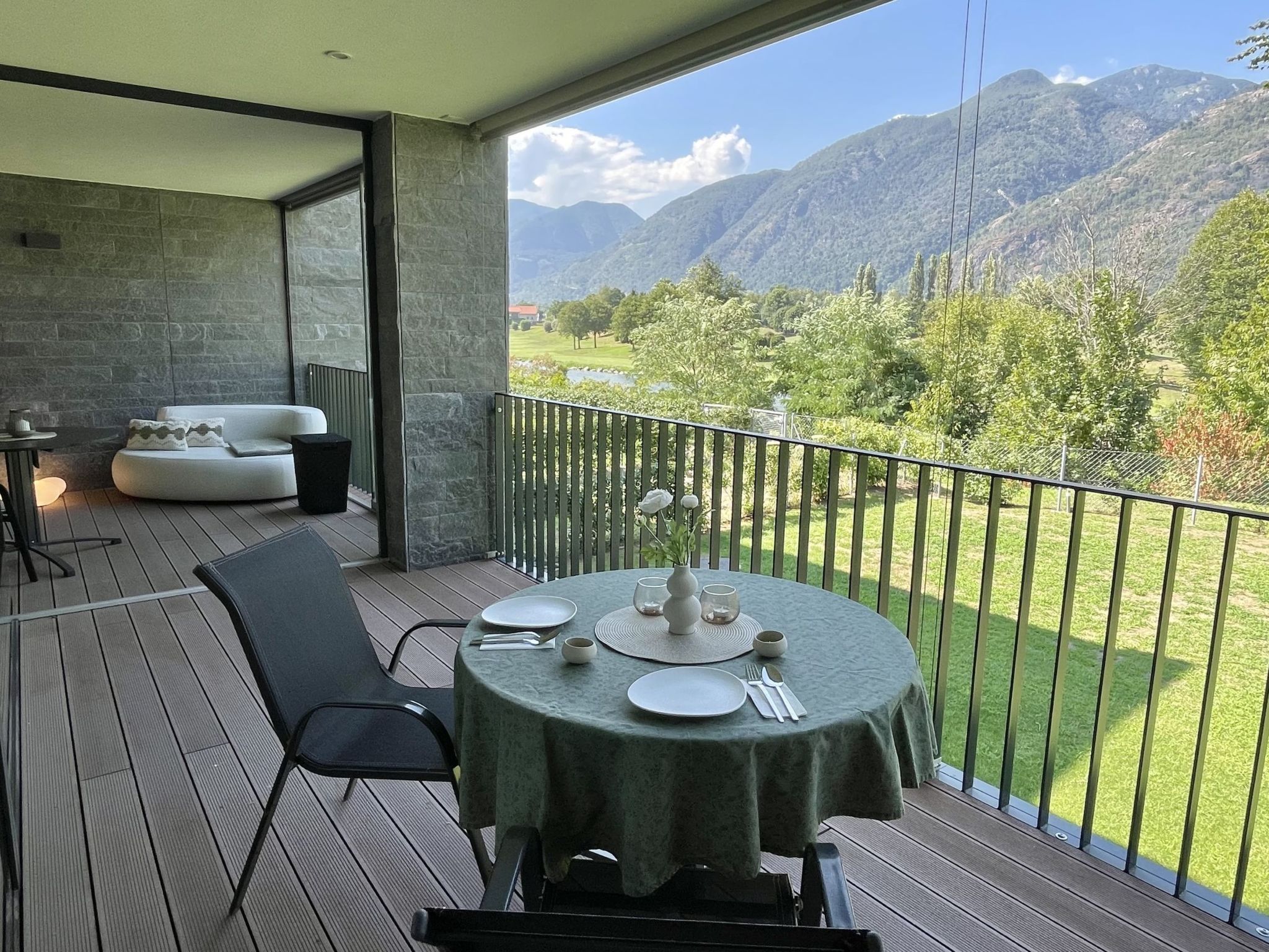 A balcony with a table set for dining, overlooking a mountainous landscape.