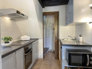 A compact kitchen with a microwave, oven, and sink. - Rustico Al Torchio by Interhome (Locarno)