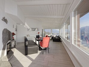 A spacious balcony with a view of the city, a dining area with a table and chairs, and a seating area with a sofa. - Casa Rondine by Interhome (Porto Ronco)