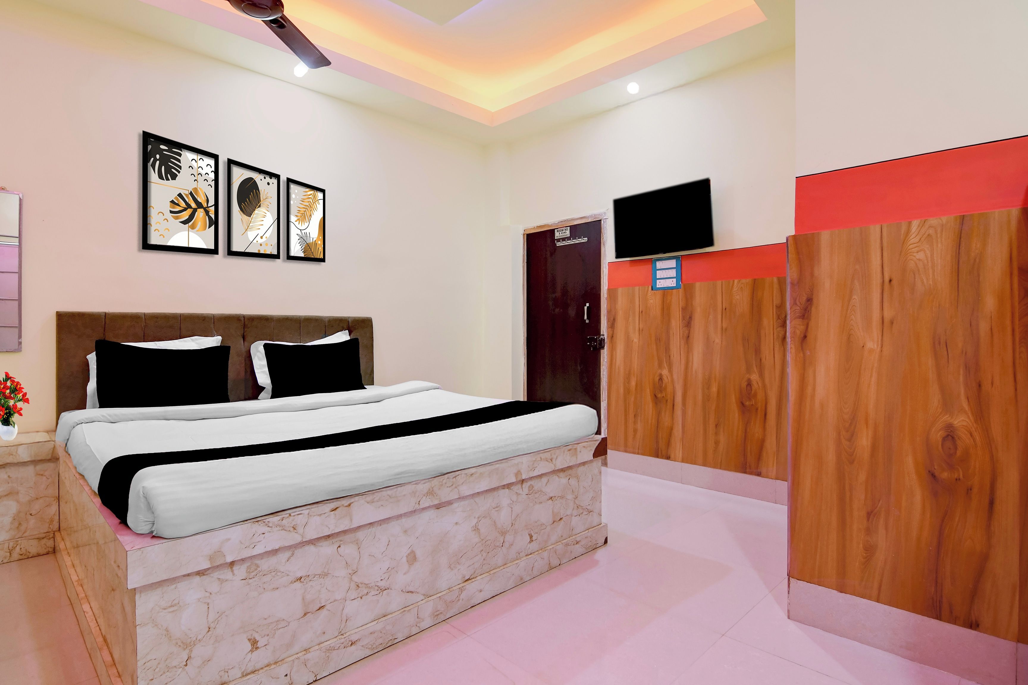 A bedroom with a bed, a wooden wardrobe, a television, and wall art.