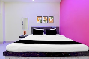 Un dormitorio moderno con una cama grande, una mesita de noche, un espejo y tres cuadros en la pared.