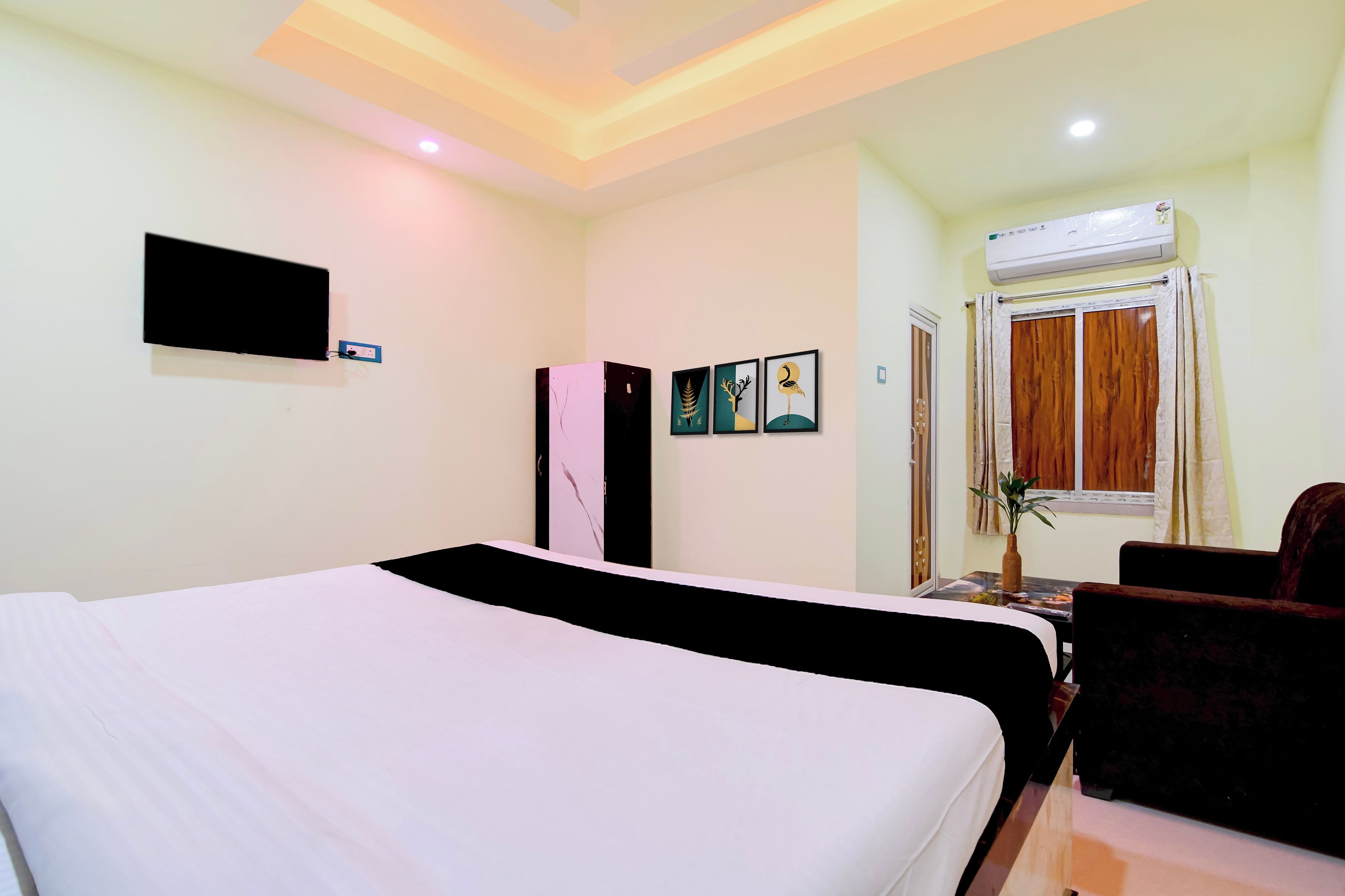 Quarto de hotel com duas camas, televisão de tela plana na parede e janela com cortinas.