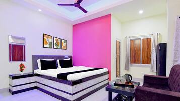 A modern bedroom with a bed, a ceiling fan, artwork, a window with curtains, and a coffee table.