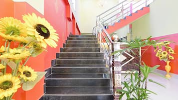 Una escalera con escalones negros, barandilla y pasamanos. Girasoles colocados a la izquierda de la escalera.