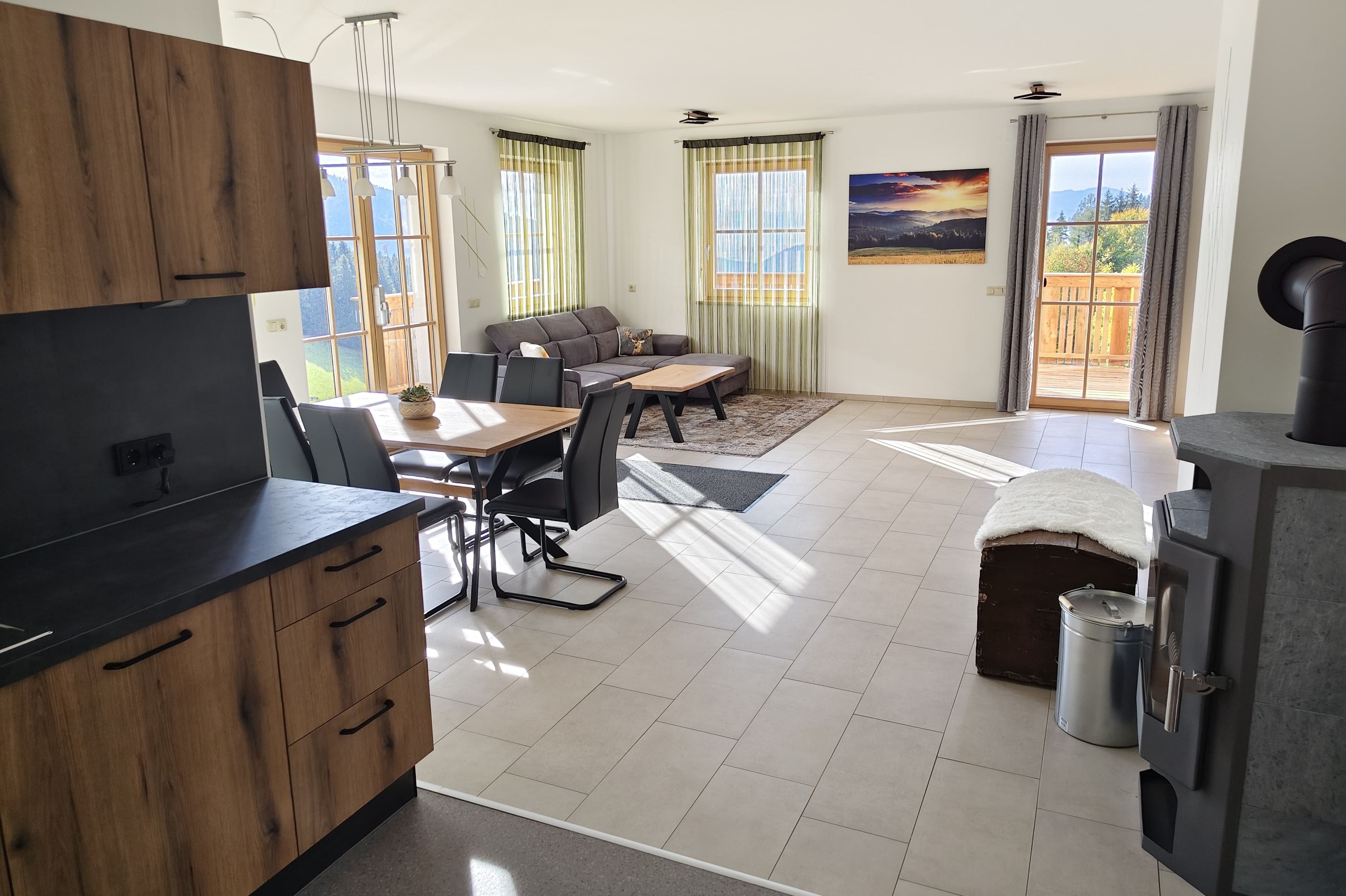 A modern kitchen with a dining area, a sofa, and a view of the outdoors.