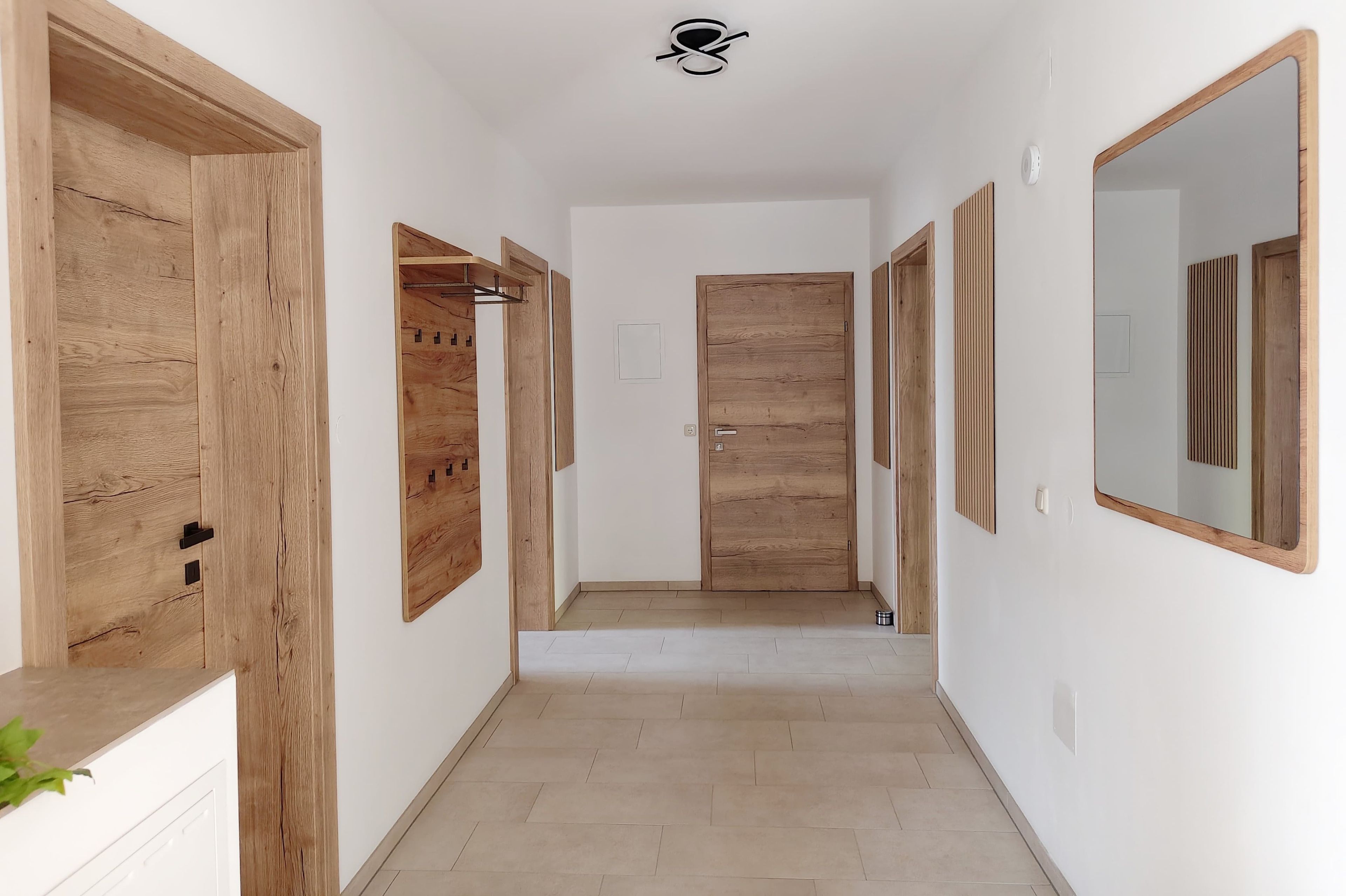 Ein Flur mit Holztüren, einem Kleiderständer und einem Spiegel an der Wand.