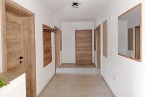 A hallway with wooden doors, a coat rack, and a mirror on the wall.