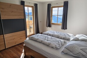 Een kamer met een bed, twee ramen en uitzicht op de omgeving.