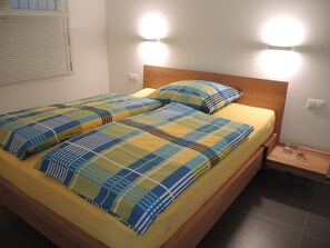 A double bed with a plaid bedspread and two bedside lamps. - Apartment Nibbio by Interhome (Minusio)