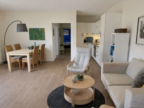 Ein modernes Wohnzimmer mit einer Couch, einem runden Couchtisch und einem Essbereich mit Tisch und Stühlen.