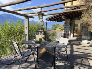 Een terras buiten met een tafel, stoelen, een lantaarn en uitzicht op bergen.