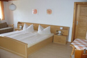 Un dormitorio con una cama de madera, dos mesitas de noche y una puerta de madera.