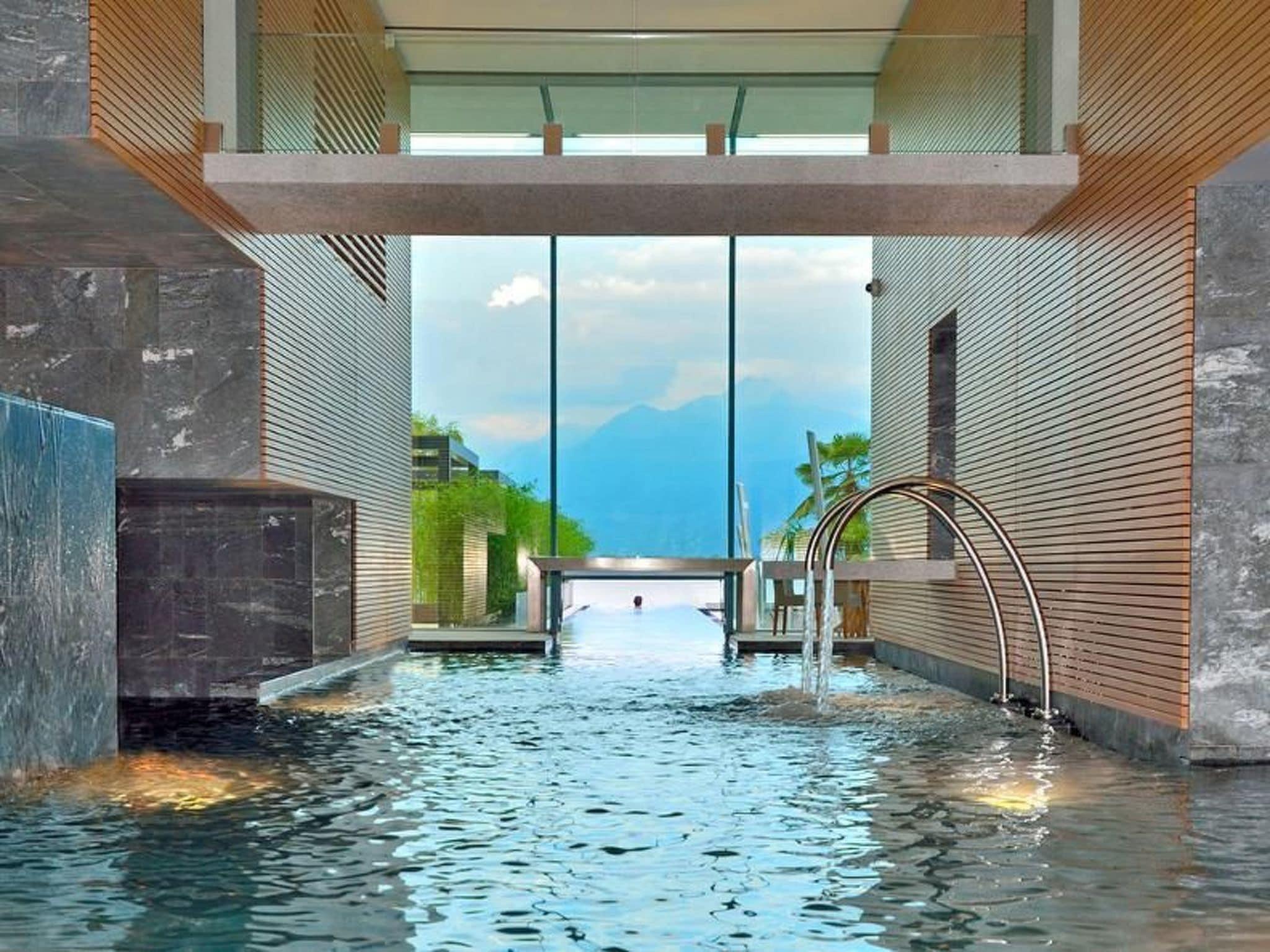 A modern indoor pool with a clear view of the sky and mountains in the background.