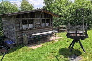 A rustic wooden cabin with a picnic table and a barbecue grill in a grassy backyard. - Holiday home with 5 bedrooms (Riedlhütte)