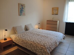 A bedroom with a bed, two bedside tables, a dresser, and two wall-mounted paintings. - Apartment Tista by Interhome (Ascona)