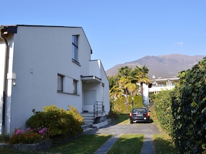 A modern two-story building with a flat roof, a visible staircase leading to the entrance, and a car parked in the driveway. - Apartment Tista by Interhome (Ascona)
