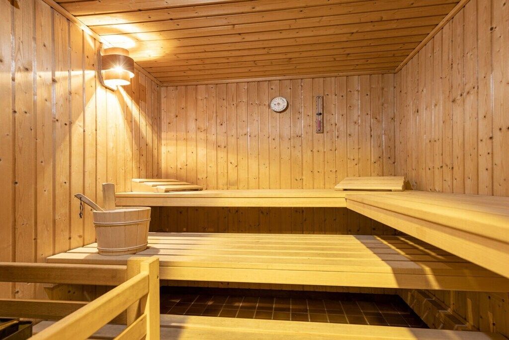 Una sauna con bancos de madera y un cubo.
