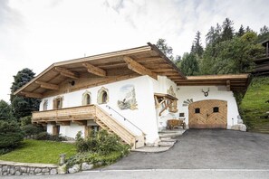 Un chalet traditionnel doté d’un toit à pente, d’un escalier en bois et d’une entrée avec une porte en bois.