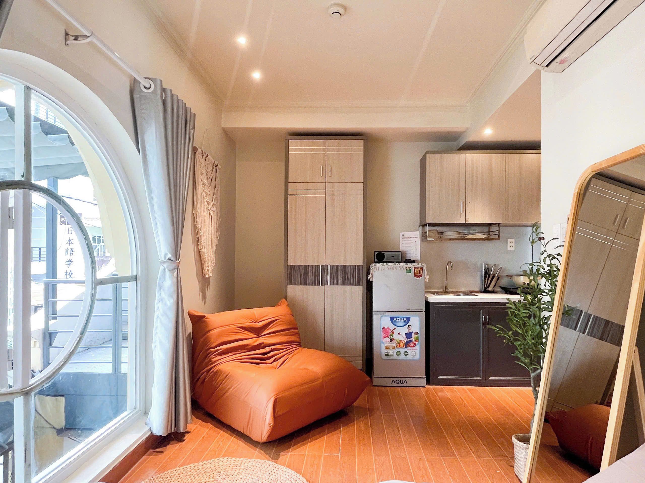 A compact living space with a kitchenette, a sofa, and a large window.