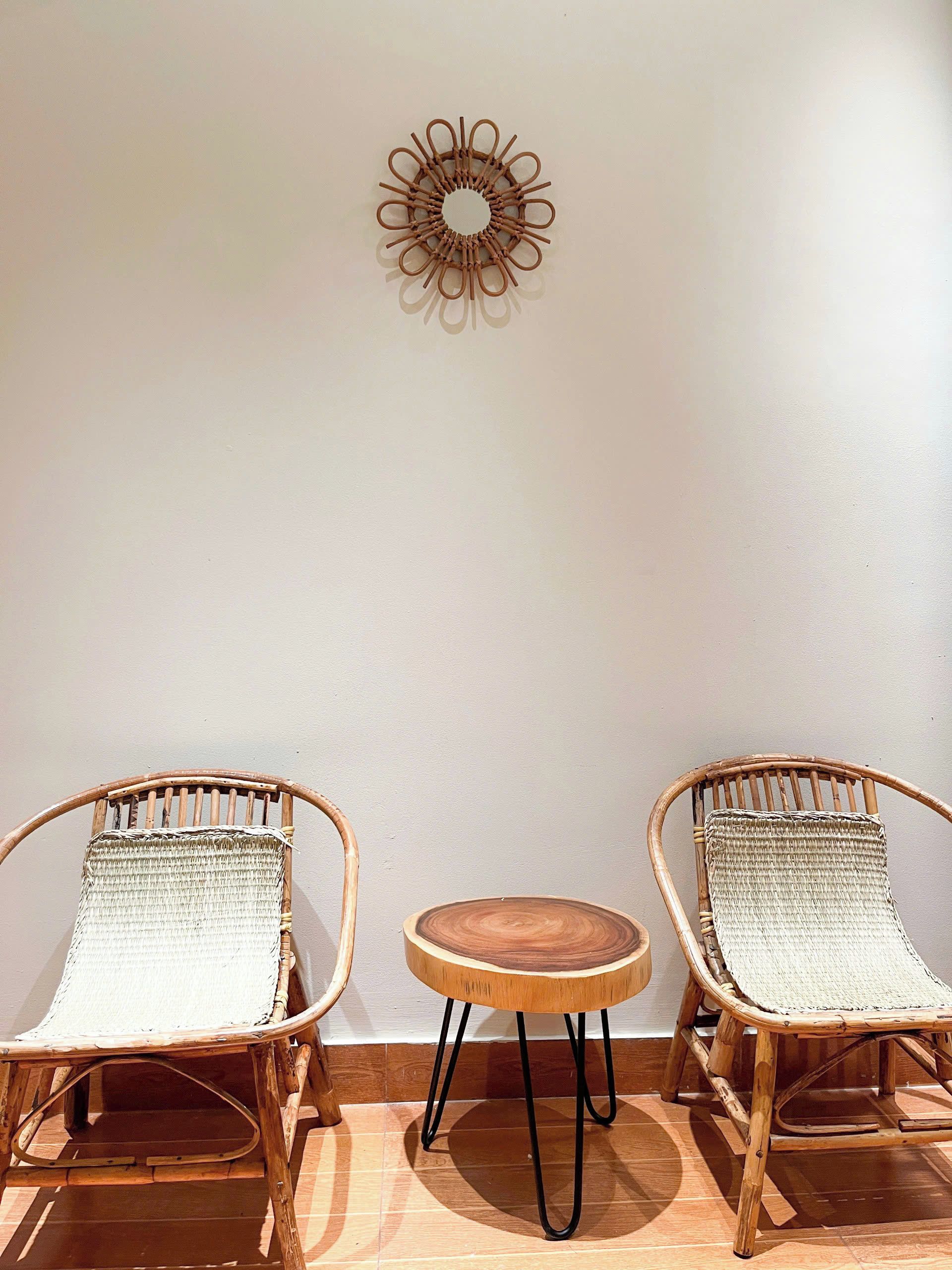 Two wicker chairs with woven seats and backs, a small wooden table with a round top, and a wall-mounted decorative item.