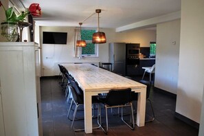 A modern kitchen with a central island, pendant lighting, and a dining area with chairs. - Hopman de Rijklaan 6 (Vrouwenpolder)
