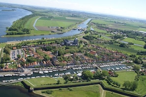 An aerial view of a riverside town with a castle, marina, and surrounding fields. - Hopman de Rijklaan 6 (Vrouwenpolder)