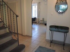 A staircase leading to a room with a radiator, a glass table, and a mirror on the wall. - Casa Felice by Interhome (Brissago)