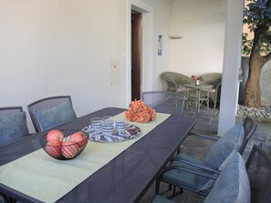 Een terras met een tafel voor vier personen, omringd door stoelen.