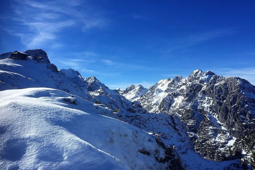 Un paysage montagneux enneigé, avec un terrain rocheux et un ciel dégagé.