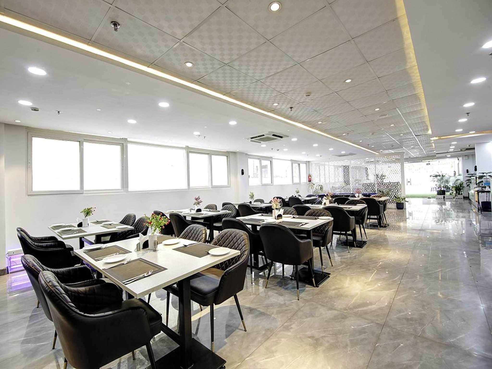 A spacious indoor dining area with multiple tables and chairs, large windows, and a polished floor.