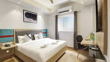 Ein Hotelzimmer mit Bett, Nachttisch, Schreibtisch, Stuhl und Deckenventilator.