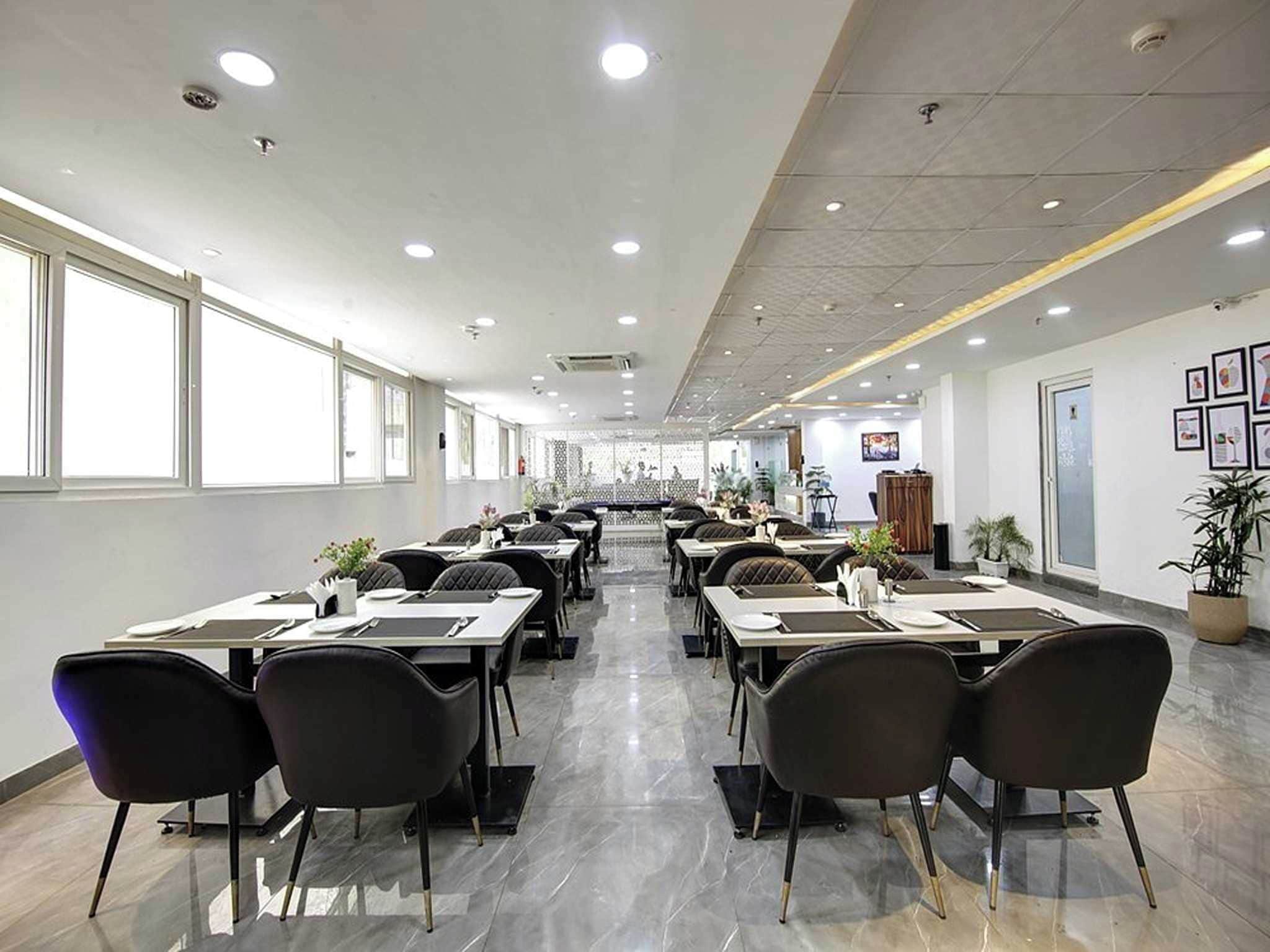 A spacious indoor dining area with multiple tables and chairs, large windows on one side, and a clean, modern design.