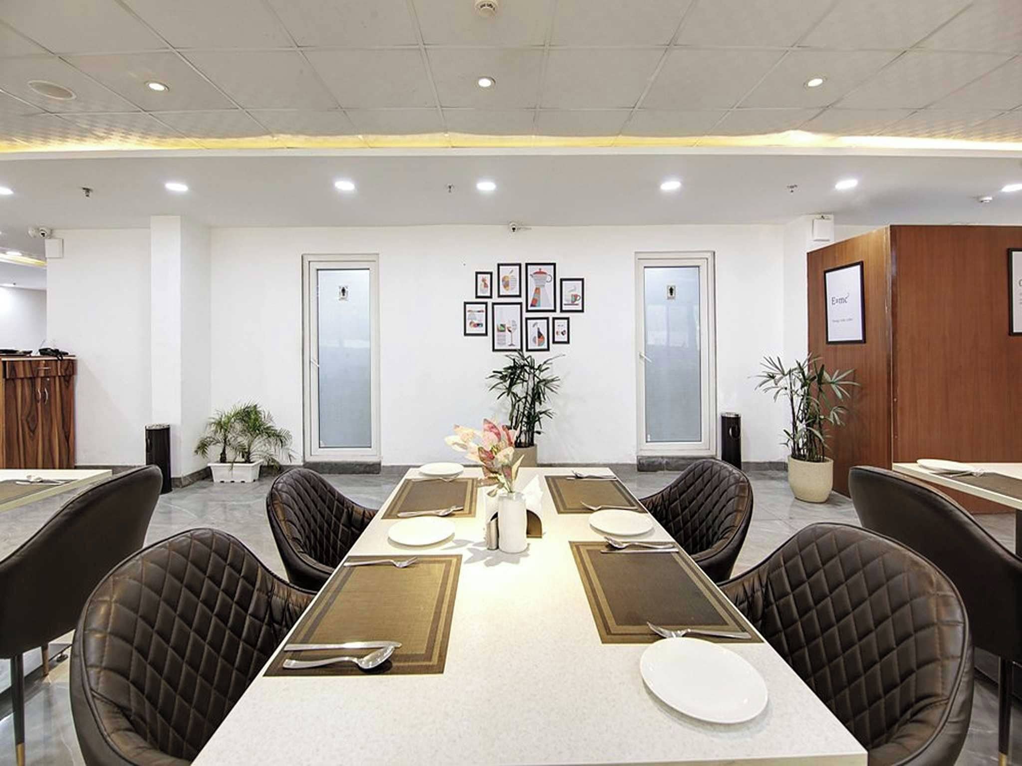 A conference room with a long table, black leather chairs, and framed pictures on the wall.