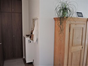 Ein Badezimmer mit einem Holzkabinent, einem Handtuchhalter mit einem weißen Handtuch, einer hängenden Pflanze und einer Uhr an der Wand.