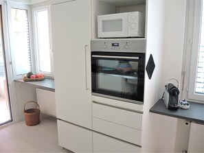 Eine Küche mit Mikrowelle, Backofen und Kaffeemaschine auf der Arbeitsfläche.