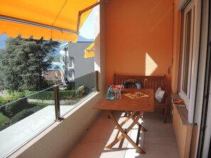 Ein Balkon mit einem Holztisch, einem Stuhl und einem kleinen Schachbrett.