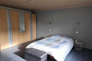 Ein Schlafzimmer mit einem Bett, einer Sitzbank, einem Kleiderschrank und einem kleinen runden Tisch.