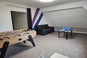 Ein Zimmer mit Kicker, Sofa und Pingpong-Tisch.